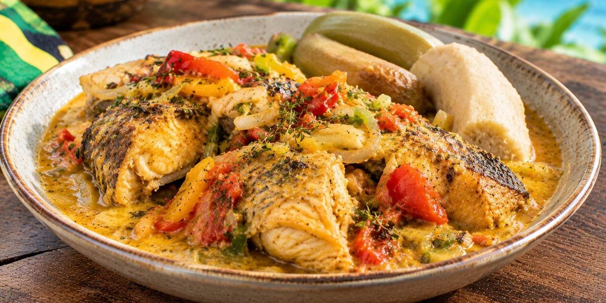 Authentic Jamaican food featuring traditional Run Down fish stew with coconut sauce and boiled sides.